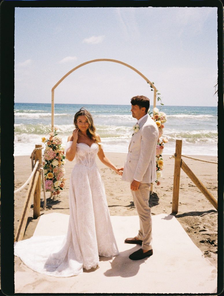 Couple holding hands at a beach wedding ceremony by the sea, 35mm film wedding photo on the Costa del Sol