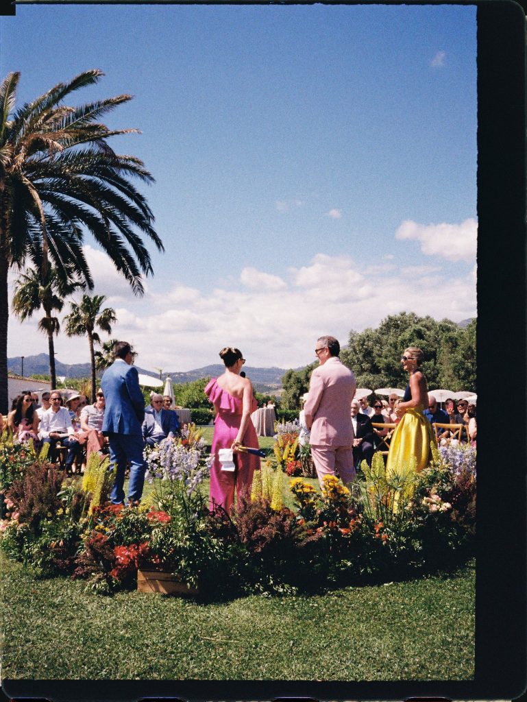 Guests in colourful outfits at an outdoor wedding ceremony, 35mm film wedding photo on the Costa del Sol