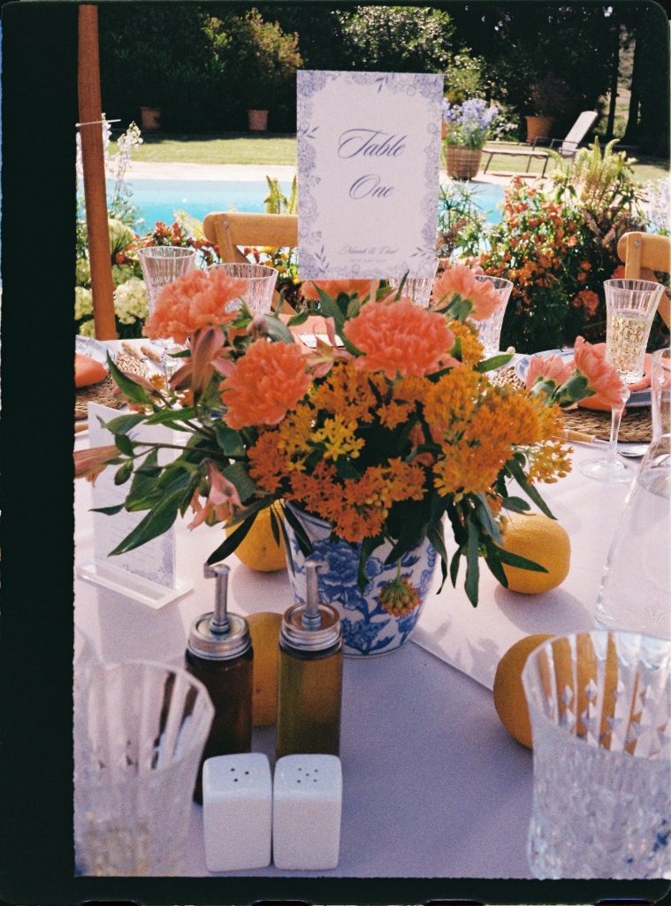 Table centrepiece with orange flowers by the pool, 35mm film wedding photo on the Costa del Sol