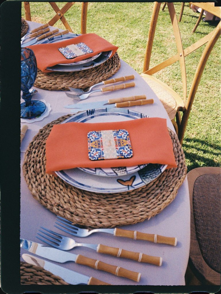 Wedding table with orange napkins and tiled plates on the lawn, 35mm film wedding photo on the Costa del Sol