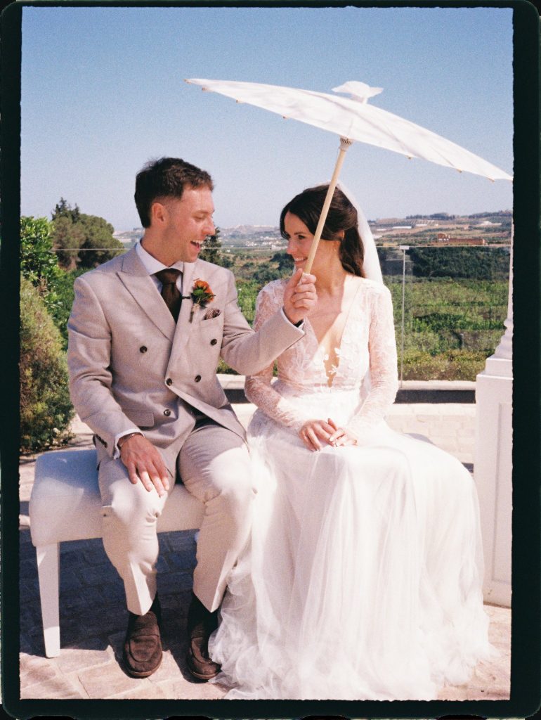 Bride holding a white parasol next to the groom, 35mm film wedding photo on the Costa del Sol
