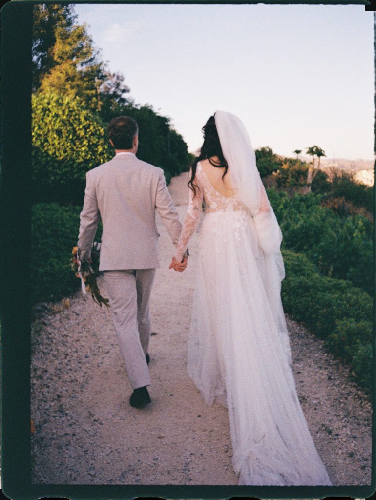 Bride and groom walking hand in hand down a garden path, 35mm film wedding photo on the Costa del Sol