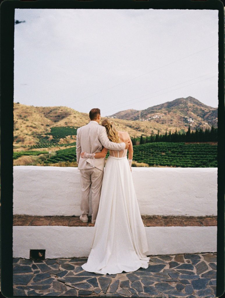Bride and groom looking out over the vineyards and mountains, 35mm film wedding photo on the Costa del Sol