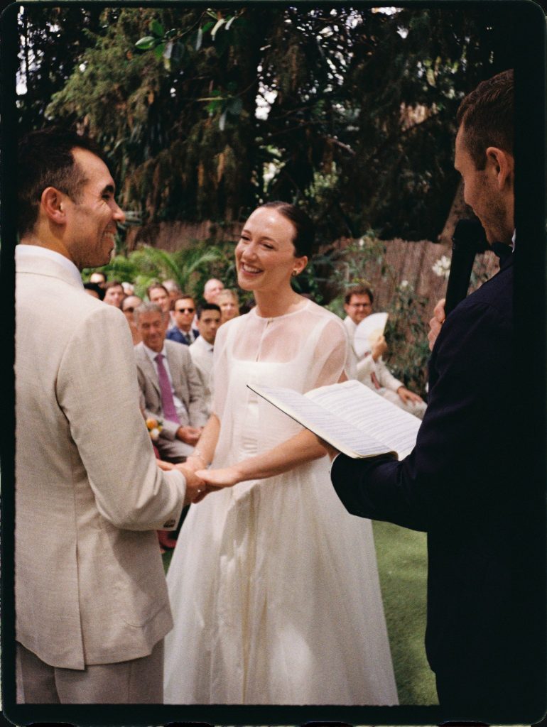 Bride laughing as she holds the groom's hands during the vows, 35mm film wedding photo on the Costa del Sol