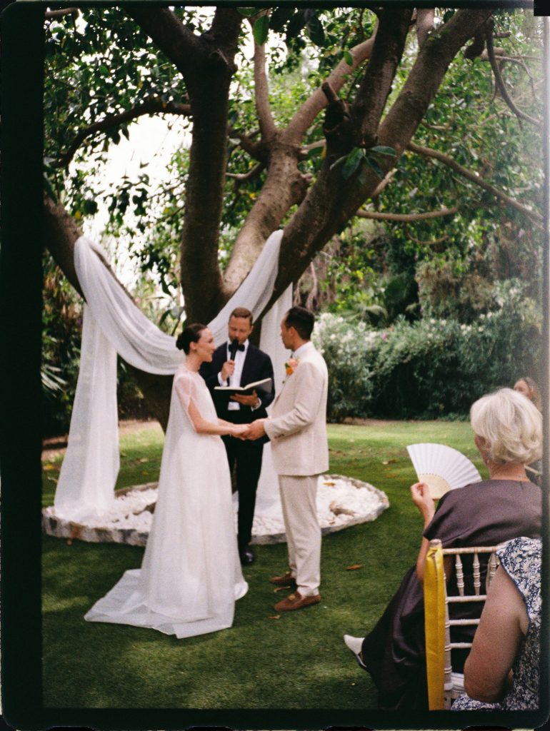 Garden wedding ceremony under a large tree with draped fabric, 35mm film wedding photo on the Costa del Sol