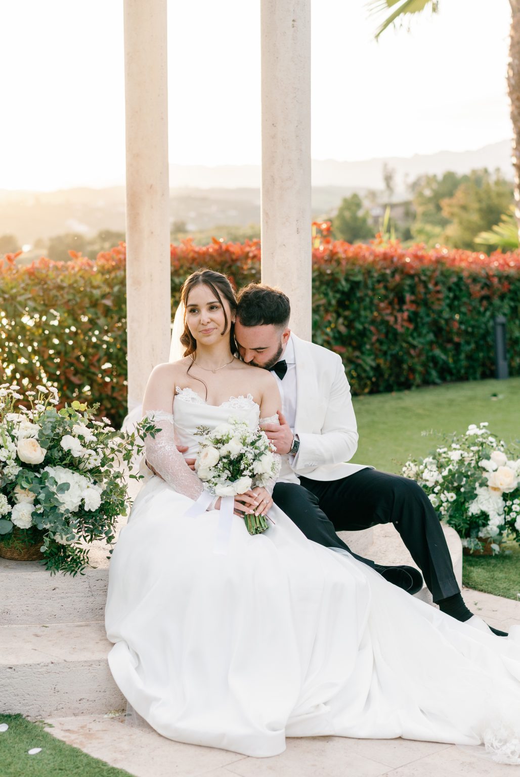 Bride and groom sitting on the steps of the white pavilion, Hotel La Viñuela wedding near Nerja